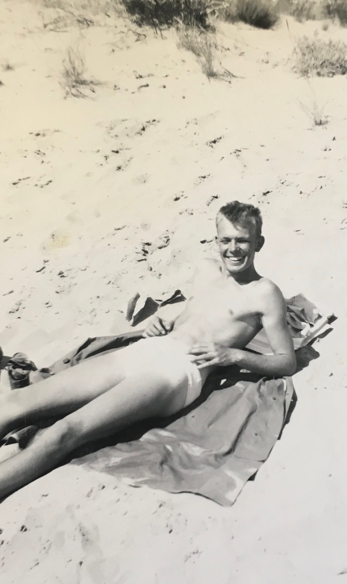 My grandfather as a young man, laughing on the sand near camp